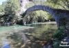 Κρυστάλλινα νερά του ποταμού Βοϊδομάτη να ρέουν ανάμεσα σε βράχια και καταπράσινη φύση.