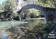 Κρυστάλλινα νερά του ποταμού Βοϊδομάτη να ρέουν ανάμεσα σε βράχια και καταπράσινη φύση.