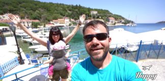 Ηλέκτρα και Ευτύχης χαμογελούν μπροστά από το γαλήνιο τοπίο της Ιθάκης, με φόντο τη θάλασσα και τα παραδοσιακά σπίτια και τη θαλασσα.
