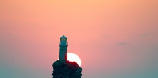 Ηλιοβασίλεμα στην Άνδρο με τον ήλιο να δύει πίσω από τον εμβληματικό φάρο Τουρλίτης.