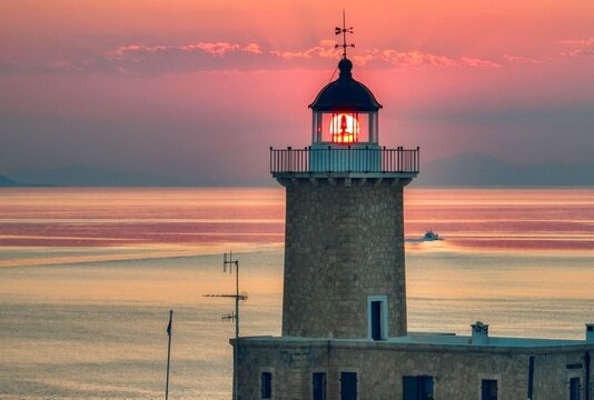 ΚΟΡΙΝΘΙΑ: Πλήρης ταξιδιωτικός οδηγός Φάρος στην Κορινθία με φόντο το ηλιοβασίλεμα και τη θάλασσα.