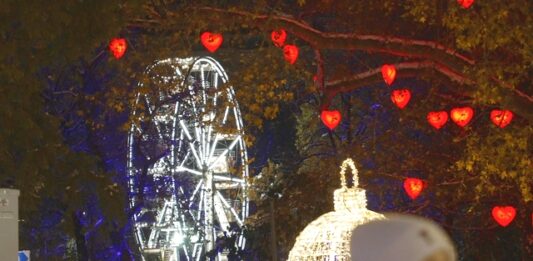 Χριστουγεννιάτικη Βιέννη φωτισμένη το βράδυ, με στολισμένους δρόμους, λαμπερά δέντρα και γιορτινή διακόσμηση σε ιστορικά κτίρια.