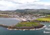 Αεροφωτογραφία του Isle of Man, που δείχνει τις καταπράσινες πλαγιές, τις παραλίες και τις ακτές του νησιού, με το μπλε της θάλασσας να αγκαλιάζει τη γη.