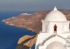 υτύχης στέκεται πάνω σε εκκλησία στην Ανάφη με φόντο τη θάλασσα.