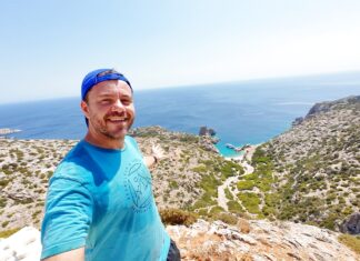Βόρεια Κάρπαθος & Σαρία: Η άγρια πλευρά του Αιγαίου Eυτύχης Μπλέτσας στέκεται μπροστά στα γαλαζοπράσινα νερά της Σαρίας, ακατοίκητου νησιού δίπλα στην Κάρπαθο, με φόντο τα βράχια και το απόλυτο γαλάζιο του Αιγαίου.