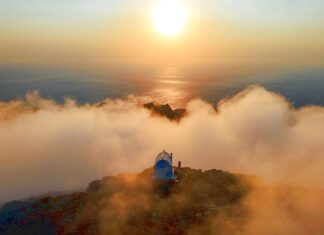 Ανατολή ηλίου από την κορυφή του Προφήτη Ηλία στην Κάρπαθο, με θέα στο Αιγαίο και χρυσαφένιο φως που λούζει το ξωκλήσι και το πέτρινο τοπίο.