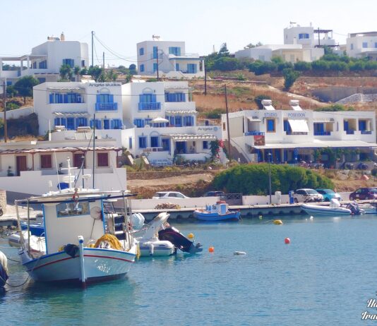 Παραδοσιακά καΐκια δεμένα στο γραφικό λιμάνι των Λειψών, με γαλήνια νερά και το χωριό στο βάθος.