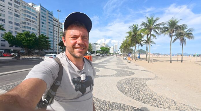 Ο Ευτύχης περπατά στον πεζόδρομο της παραλίας Copacabana στο Ρίο, με το χαρακτηριστικό ασπρόμαυρο κυματιστό μοτίβο στο δάπεδο.