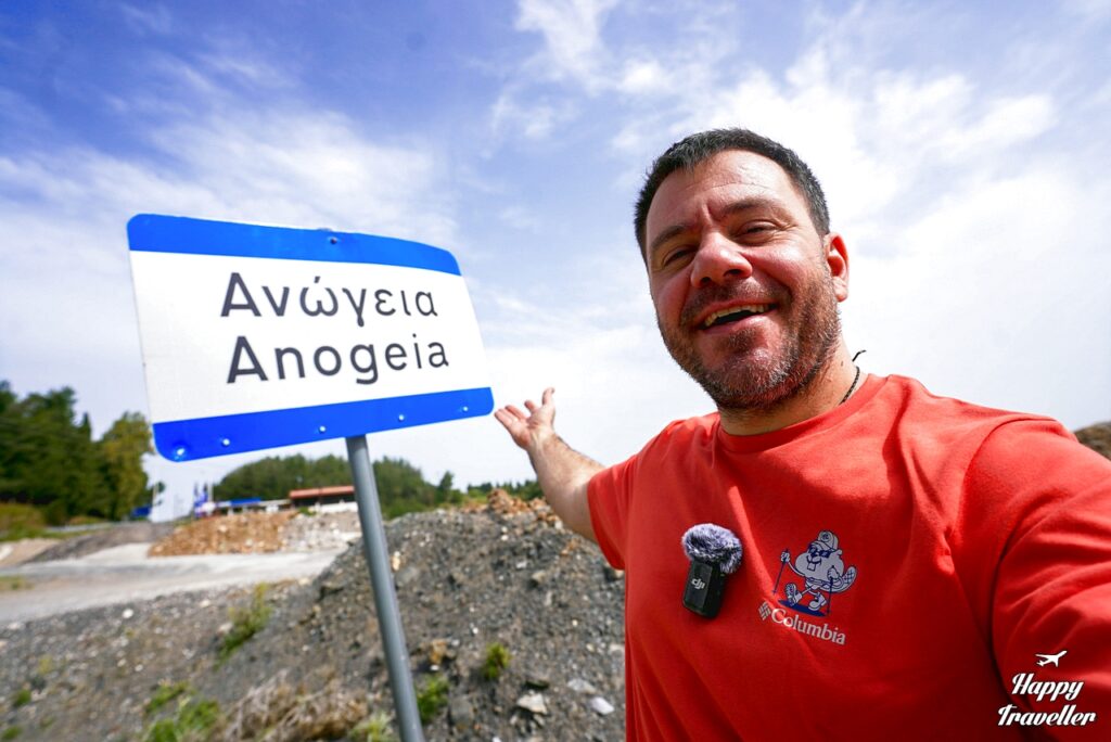 Ευτύχης Μπλέτσας ποζάρει χαμογελαστός μπροστά σε πινακίδα που γράφει «Ανώγεια».