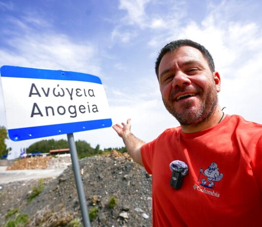 Ευτύχης Μπλέτσας ποζάρει χαμογελαστός μπροστά σε πινακίδα που γράφει «Ανώγεια».