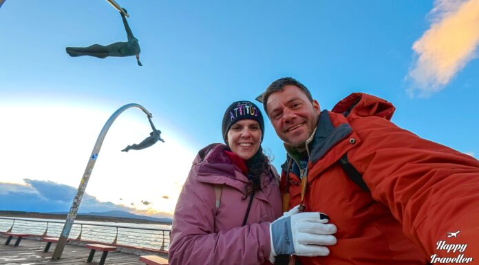 Ευτύχης Μπλέτσας και Ηλέκτρα Αστέρη στο Monumento al Viento στο Puerto Natales, ποζάρουν μπροστά από το εμβληματικό γλυπτό που συμβολίζει τους ισχυρούς ανέμους της Παταγονίας, με φόντο το παραλιακό μέτωπο και το φιόρδ Última Esperanza