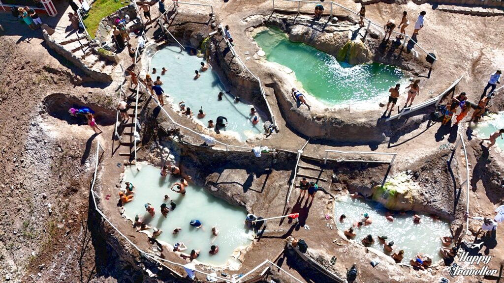 Πανοραμική θέα των θερμών πηγών Termas de Colina στις Άνδεις της Χιλής με τις φυσικές πέτρινες πισίνες σε βαθμίδες και ορεινό τοπίο γύρω.