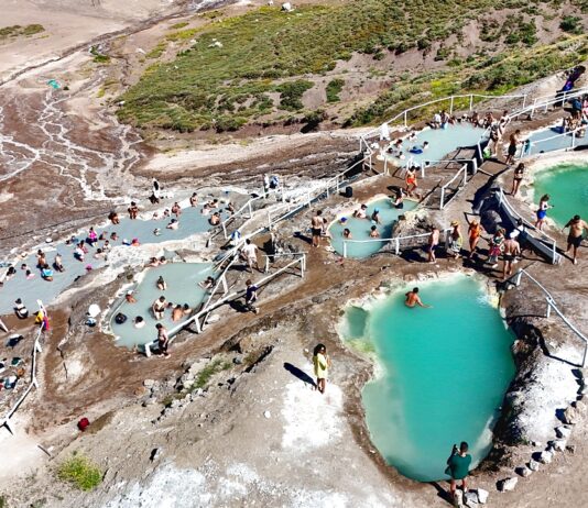 Πανοραμική θέα των Termas de Colina στις Άνδεις της Χιλής με φυσικές θερμές πισίνες σε πετρόχτιστες βαθμίδες και ορεινό τοπίο γύρω.