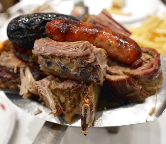 Παραδοσιακό ασάδο σερβιρισμένο στο πιάτο, με ποικιλία από κομμάτια κρέατος.